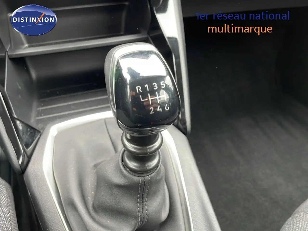 Le levier de vitesses manuel de la Peugeot 208 gris Artense, vu en gros plan depuis l'avant intérieur.