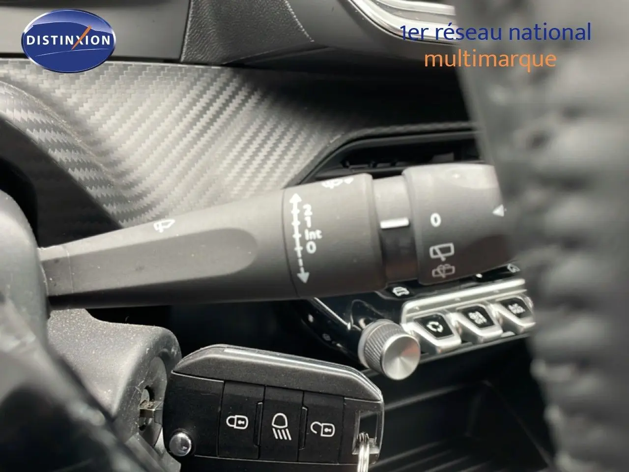 Gros plan sur la commande d'essuie-glace et les boutons de réglage, intérieur noir avec finition carbone du Peugeot 208 gris.