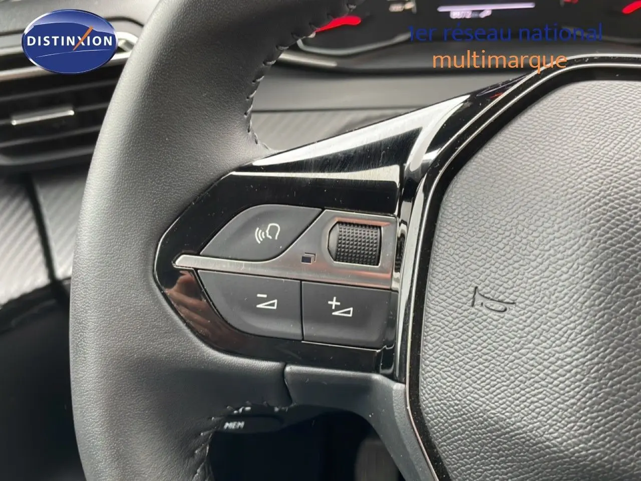 Gros plan sur le volant noir de la Peugeot 208 2025 avec commandes audio intégrées et finition brillante.