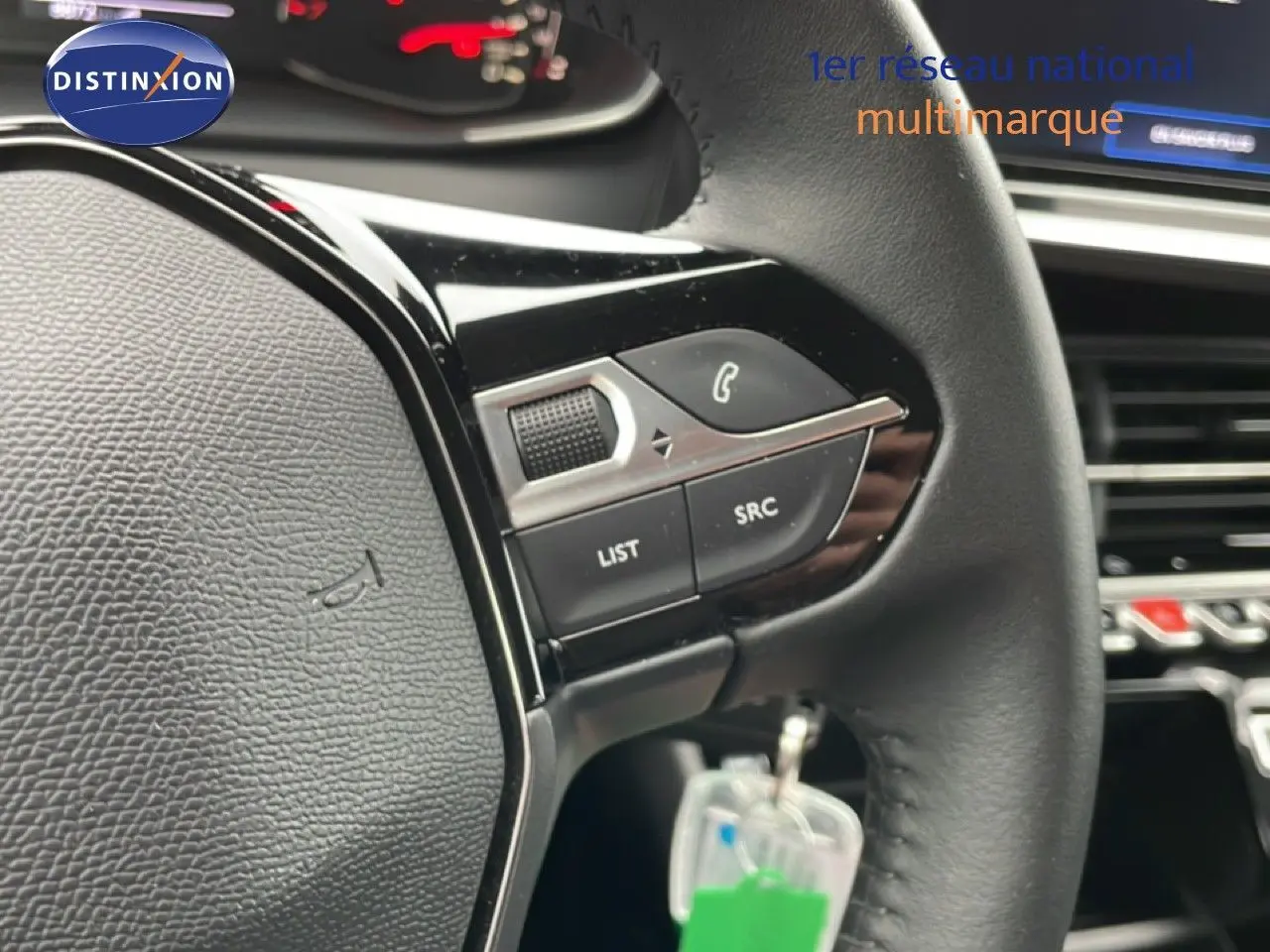 Gros plan sur le volant noir de la Peugeot 208 2025 avec commandes intégrées et tableau de bord en arrière-plan.