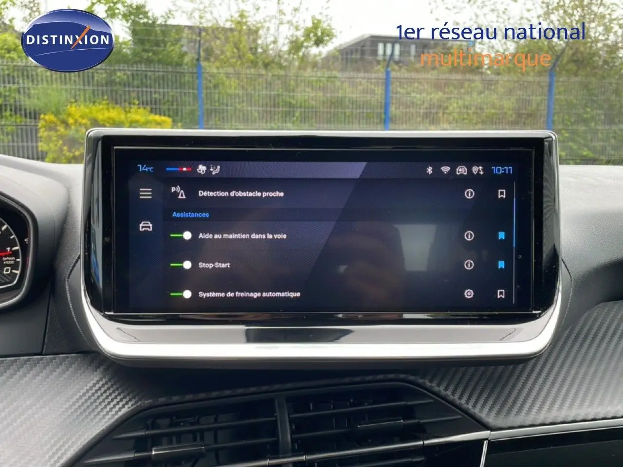 Écran tactile central du tableau de bord de la Peugeot 208 gris Artense, affichant les aides à la conduite.