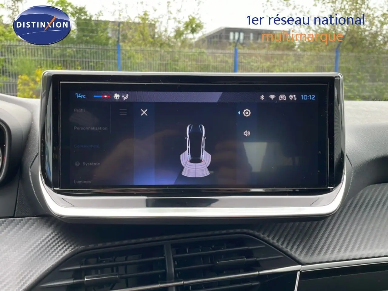 Écran tactile central affichant l'aide au stationnement dans l'habitacle d'une Peugeot 208 gris Artense.