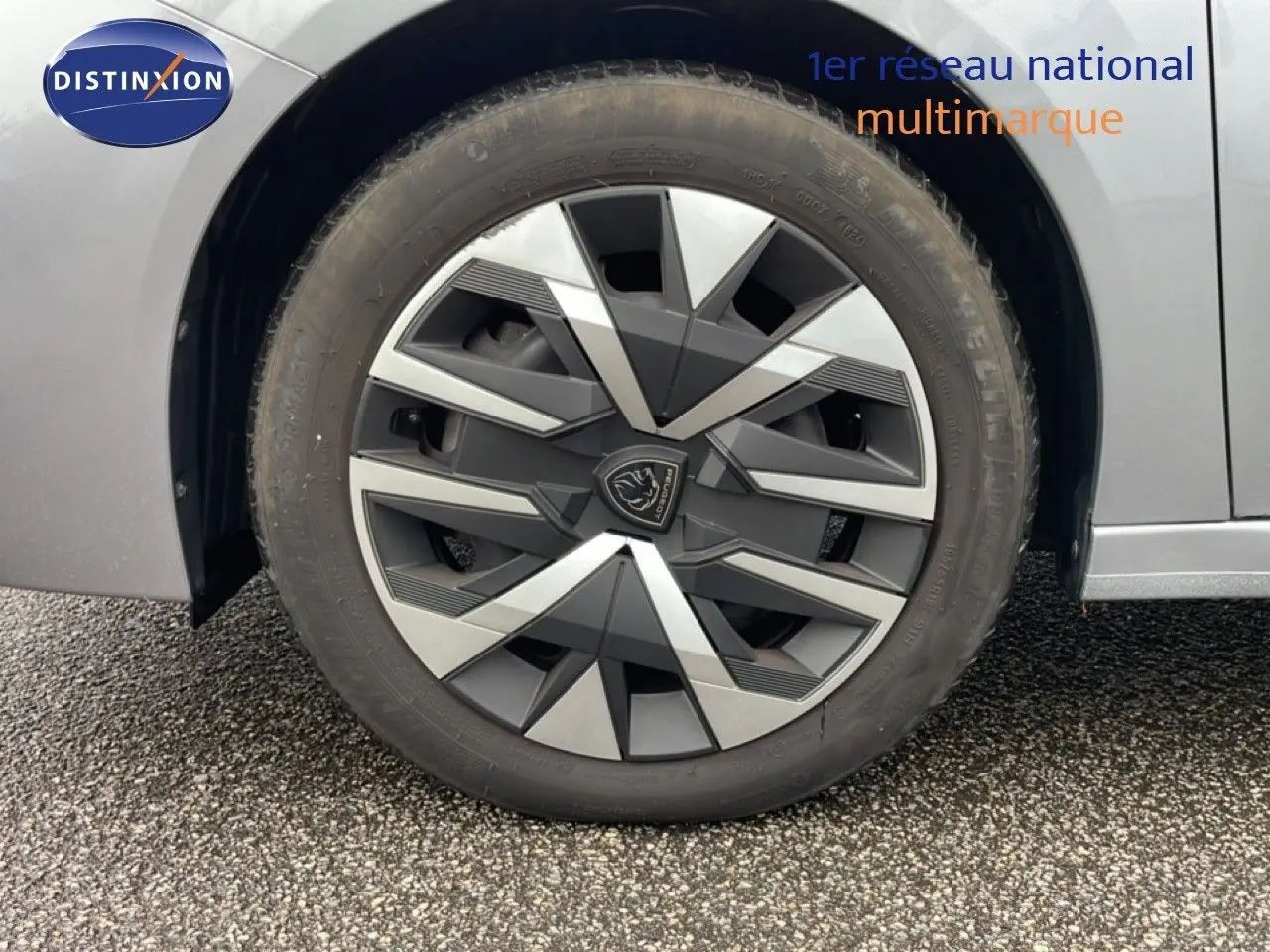 Gros plan sur la roue avant droite d’une Peugeot 208 gris Artense métal, mettant en valeur la jante au design géométrique.