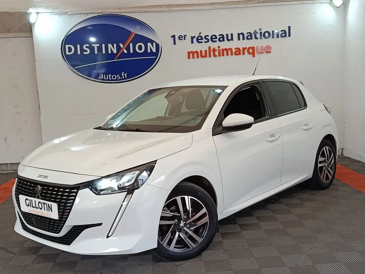 Peugeot 208 blanc vue 3/4 avant droit, avec phares LED allumés et jantes alliage distinctives.