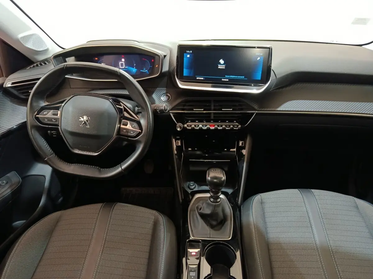 Vue intérieure avant de la Peugeot 208 PureTech 100 blanche, volant cuir, écran tactile 10 pouces et boîte manuelle.