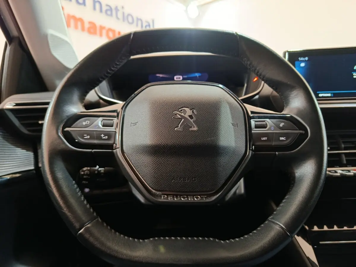 Gros plan sur le volant cuir multifonctions noir de la Peugeot 208 PureTech 100 S&S Allure Business 2021.
