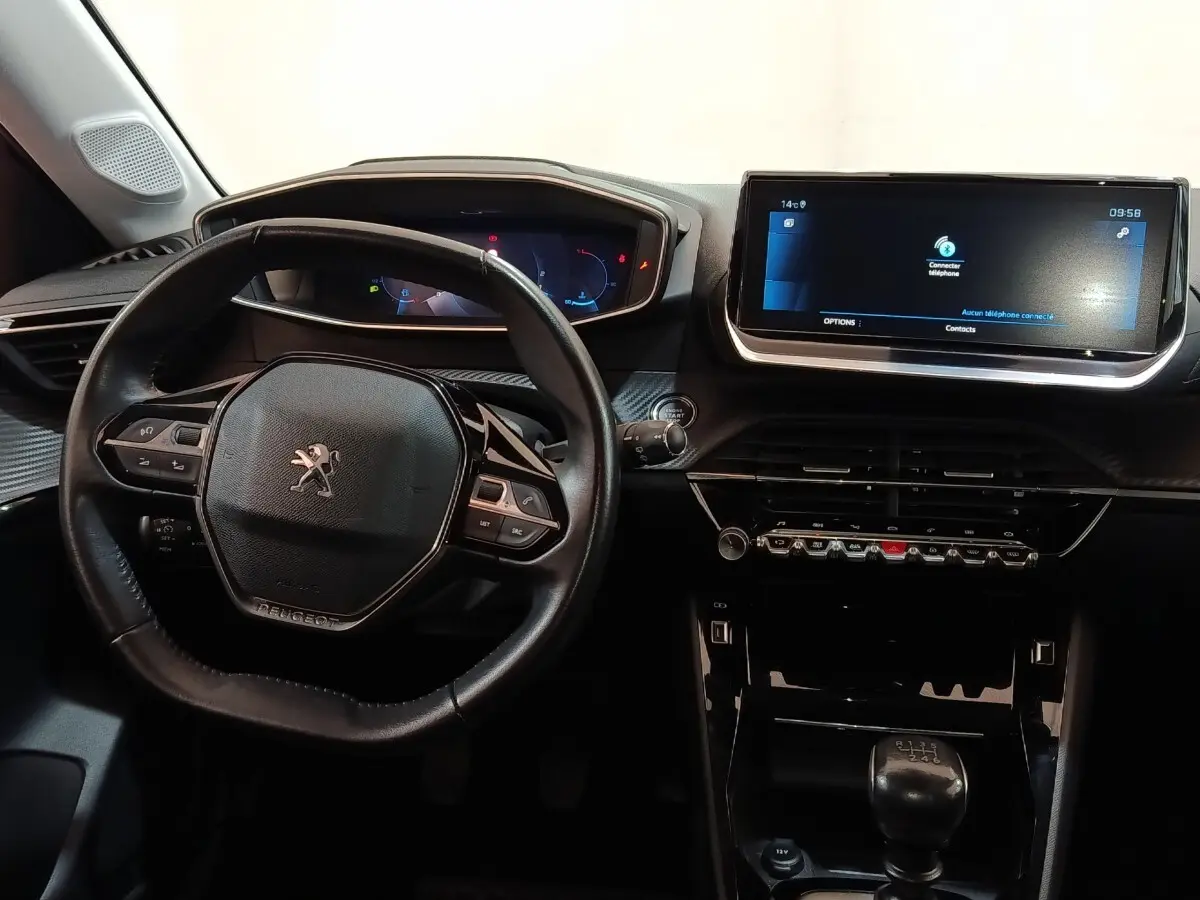 Intérieur de la Peugeot 208 blanc, vue centrée sur le volant cuir et l’écran tactile 10 pouces du tableau de bord.