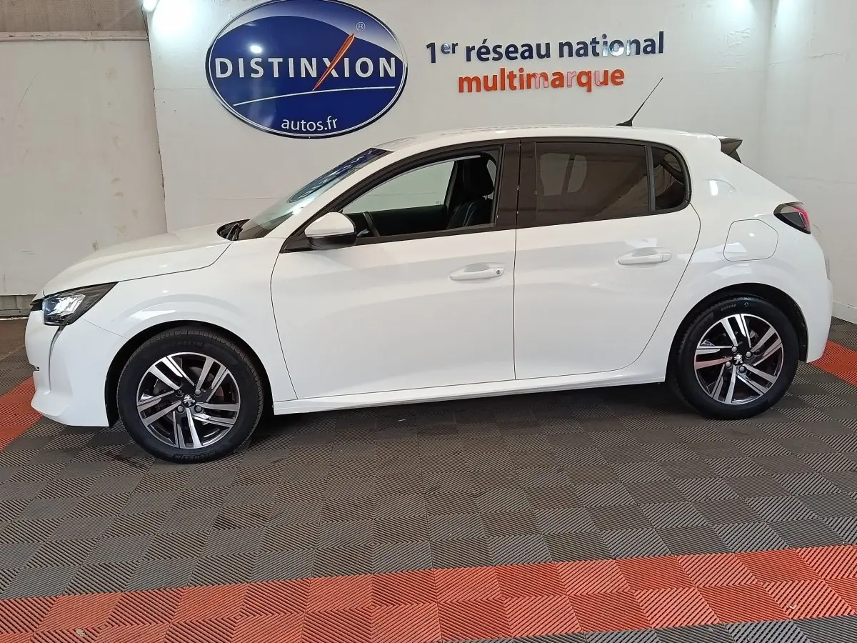 Profil droit d'une Peugeot 208 blanche 2021, finition Allure Business, avec jantes alliage et vitres teintées.