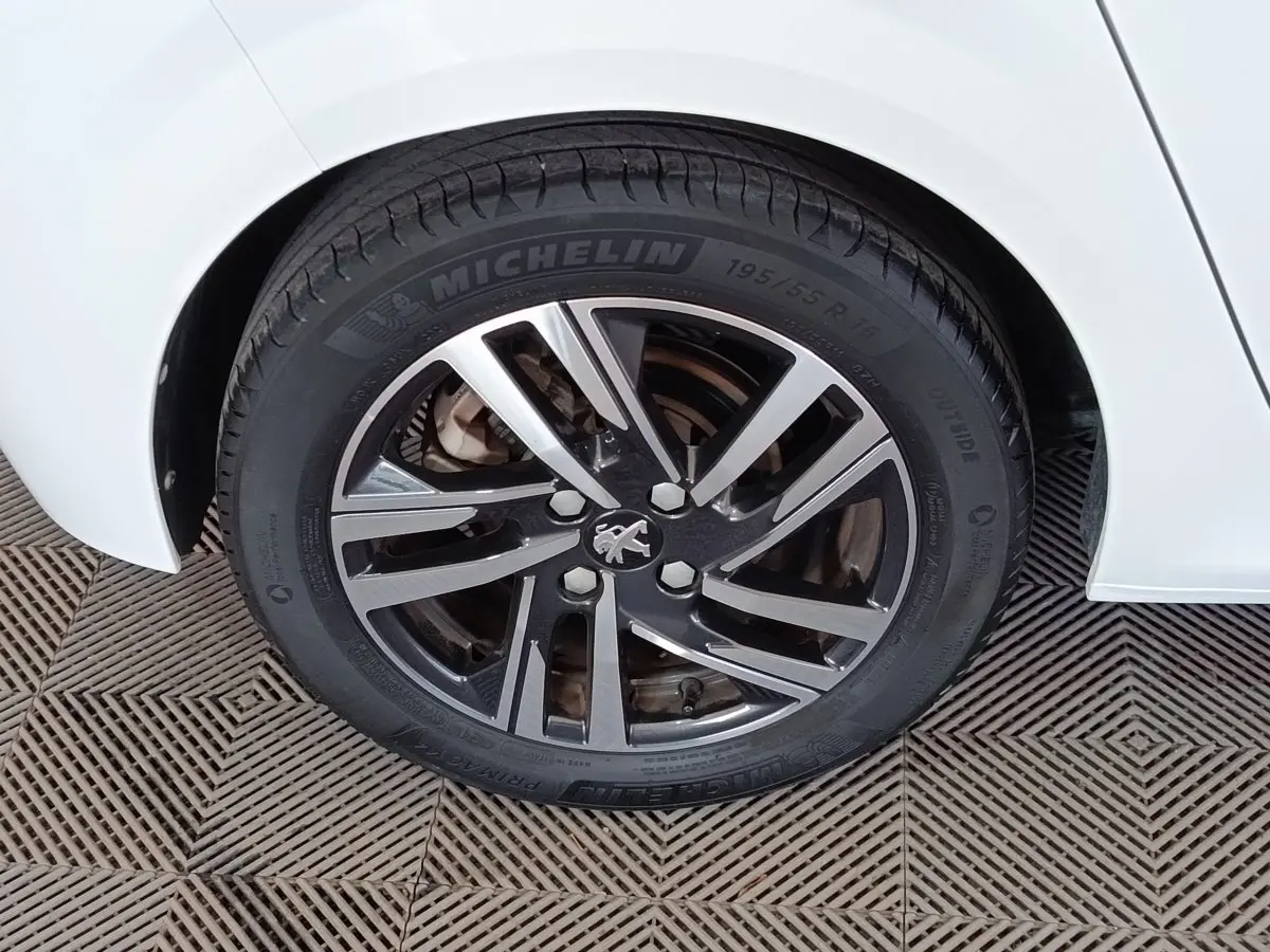 Gros plan sur la roue arrière droite d'une Peugeot 208 blanche avec jante alliage et pneu Michelin.