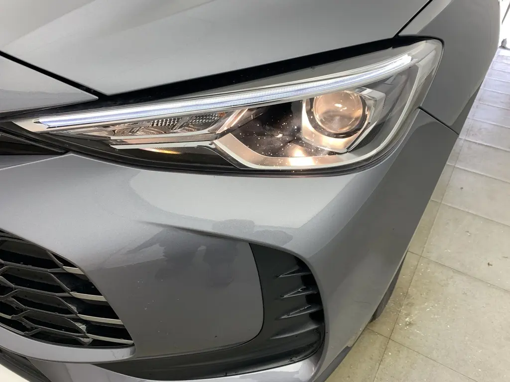 Gros plan sur le phare avant droit du MG ZS 1.5 L Hybrid+ 2026 en gris Hampstead avec calandre et prise d'air noire.