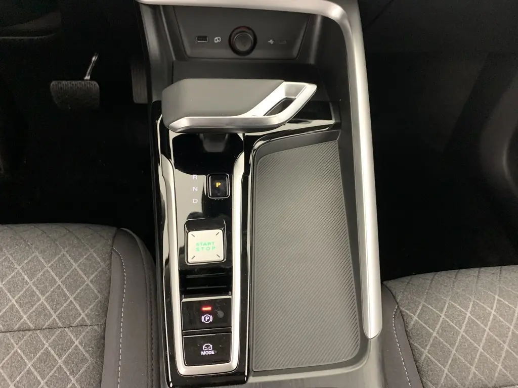 Vue plongeante sur la console centrale noire brillante du MG ZS 1.5 L Hybrid+ avec levier de vitesse et bouton start/stop.