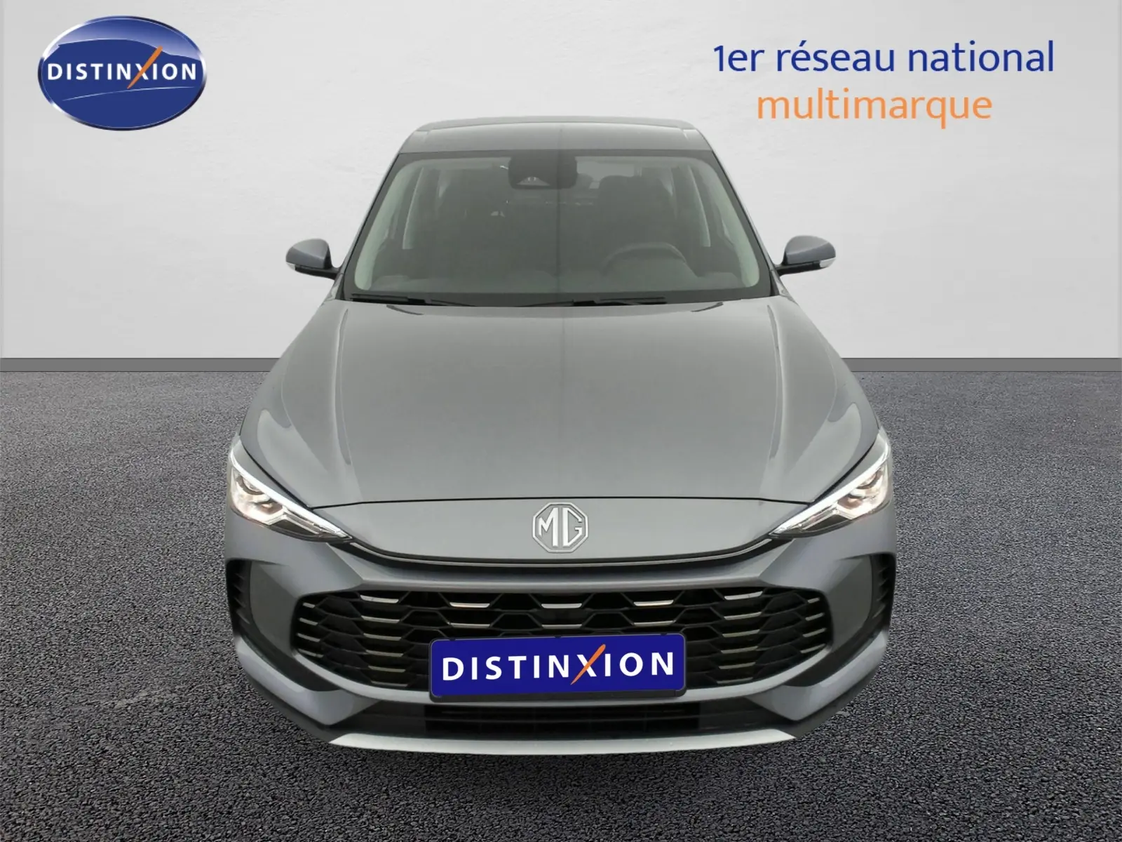 Vue avant d'un MG ZS 1.5 L Hybrid+ 197 ch en gris Hampstead avec calandre noire et phares LED allumés.