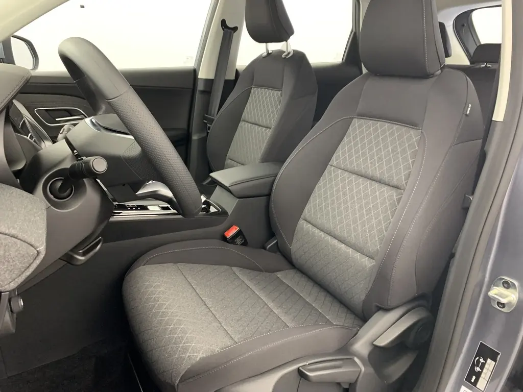 Vue intérieure côté conducteur du MG ZS 2026 avec sièges en tissu noir et gris, volant et console centrale visibles.