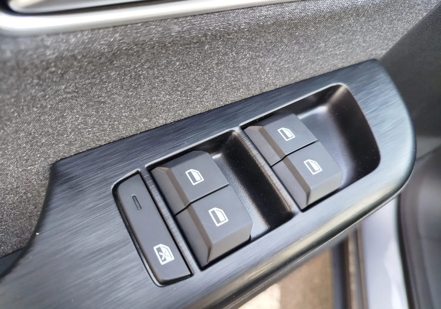 Gros plan sur les commandes des vitres électriques côté conducteur du MG ZS 1.5 L Hybrid+ 2026 en Hampstead Grey.