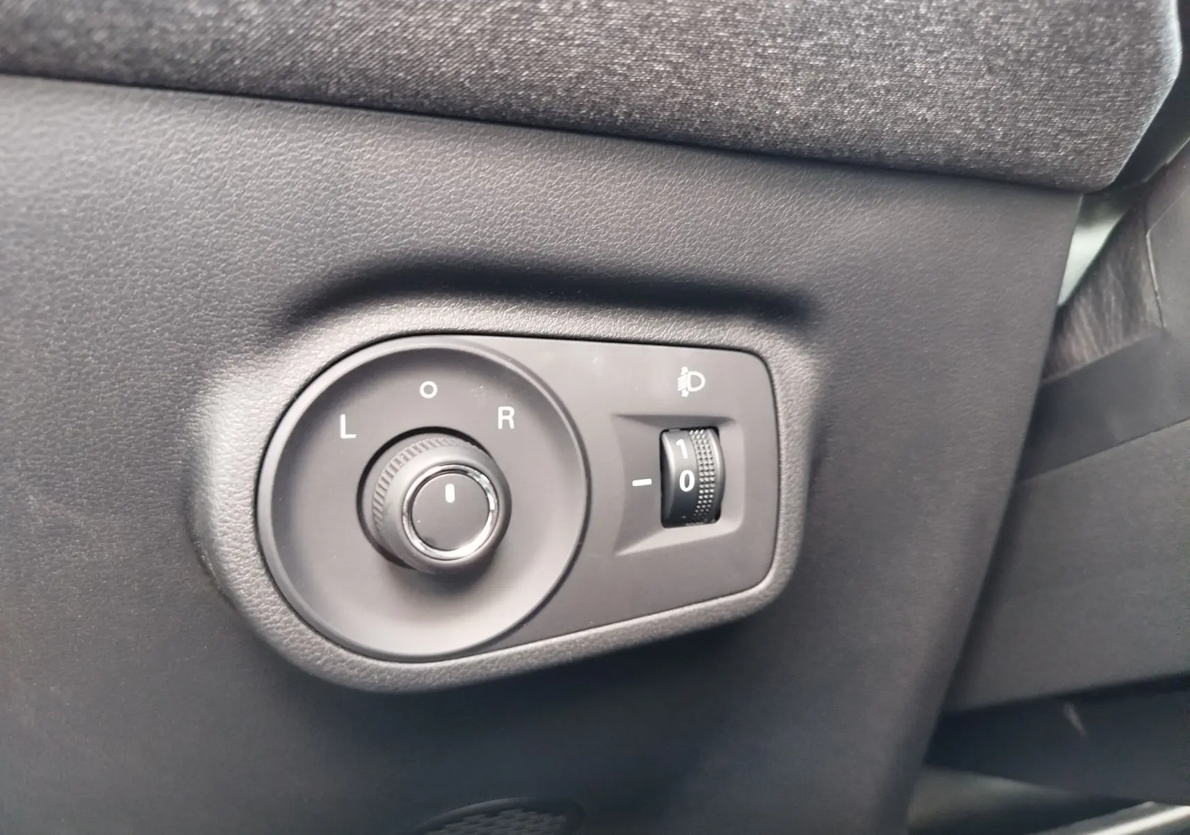 Gros plan sur les commandes de réglage des rétroviseurs et des phares intérieures du MG ZS 1.5 L Hybrid+ 2026 en Hampstead Grey.