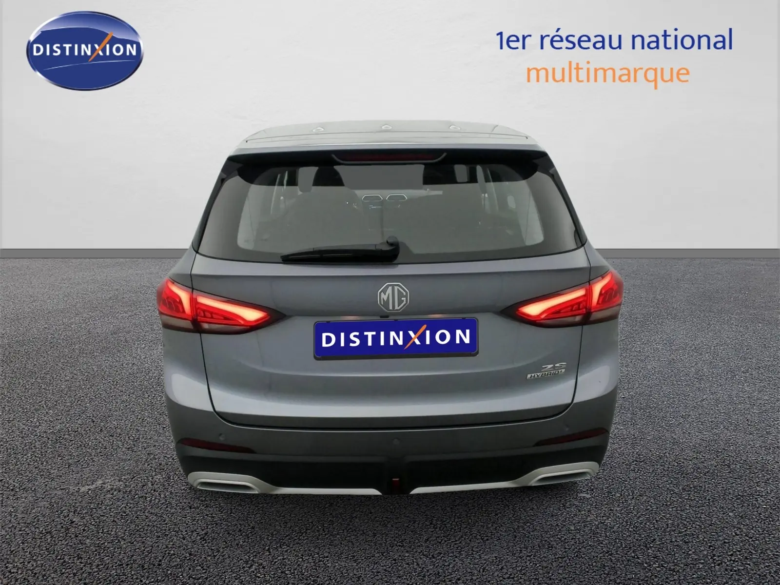Vue arrière du SUV MG ZS 1.5 L Hybrid+ en gris Hampstead avec feux LED allumés et double sortie d'échappement intégrée.