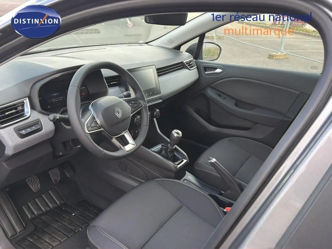 Vue intérieure côté conducteur de la Renault Clio gris foncé 2026 avec tableau de bord moderne et boîte manuelle.