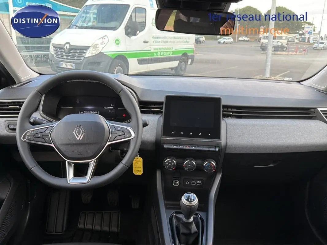 Vue intérieure avant de la Renault Clio gris foncé 2026, volant multifonction, écran tactile et levier de vitesse manuel visible.