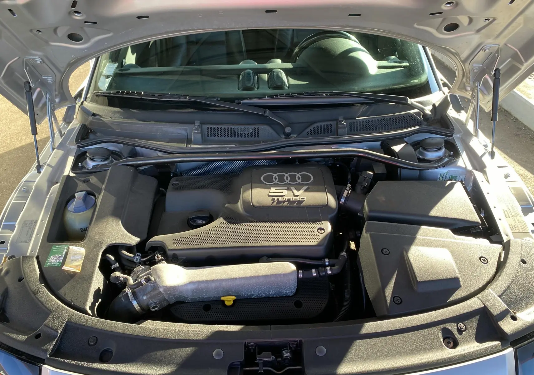 Vue rapprochée du moteur 5V turbo sous le capot ouvert d'une Audi TT Coupé gris de 2002.