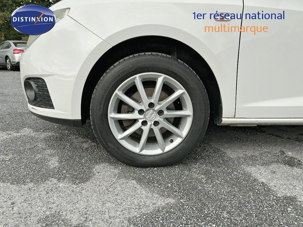 Gros plan sur la roue avant gauche d'une SEAT Ibiza blanche 2010, mettant en valeur la jante alliage et le passage de roue.