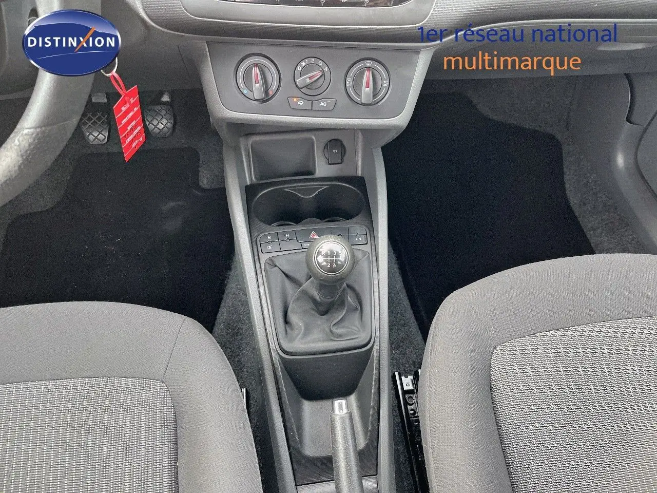 Vue intérieure centrée sur la console centrale d'une SEAT Ibiza blanche 2010 avec levier de vitesse manuel et commandes climatiques.