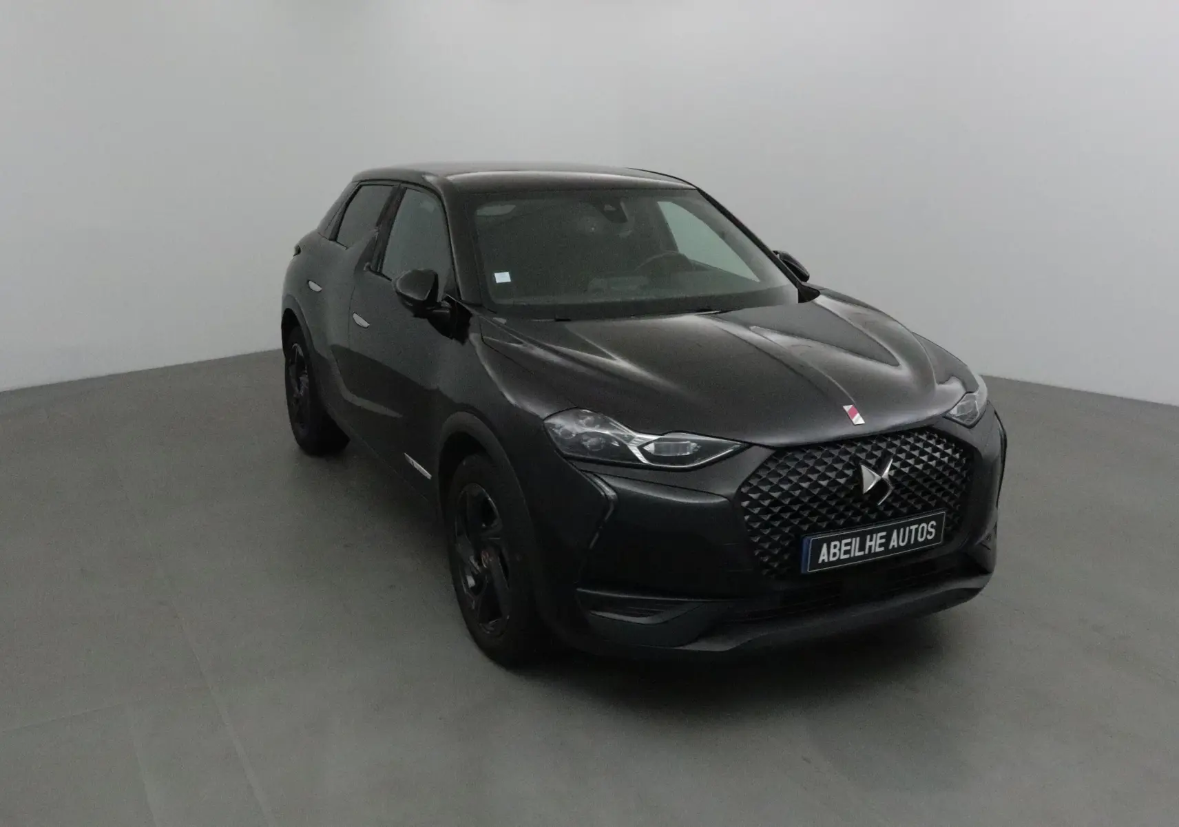 DS3 Crossback noir en 3/4 avant droit, avec calandre distinctive et phares LED DS Vision allumés.