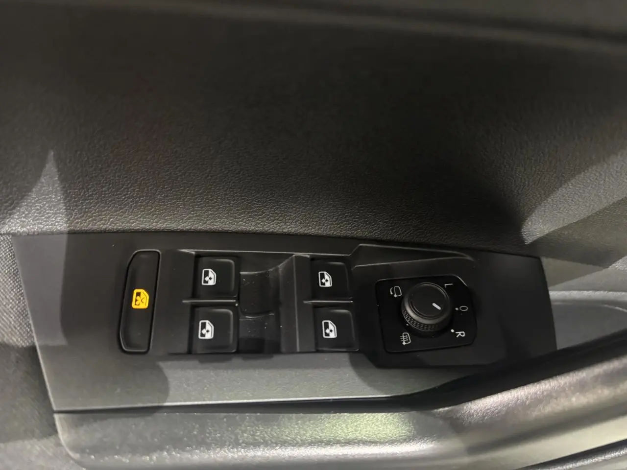 Gros plan sur les commandes de lève-vitres et réglage des rétroviseurs côté conducteur du Volkswagen Taigo blanc 2023.