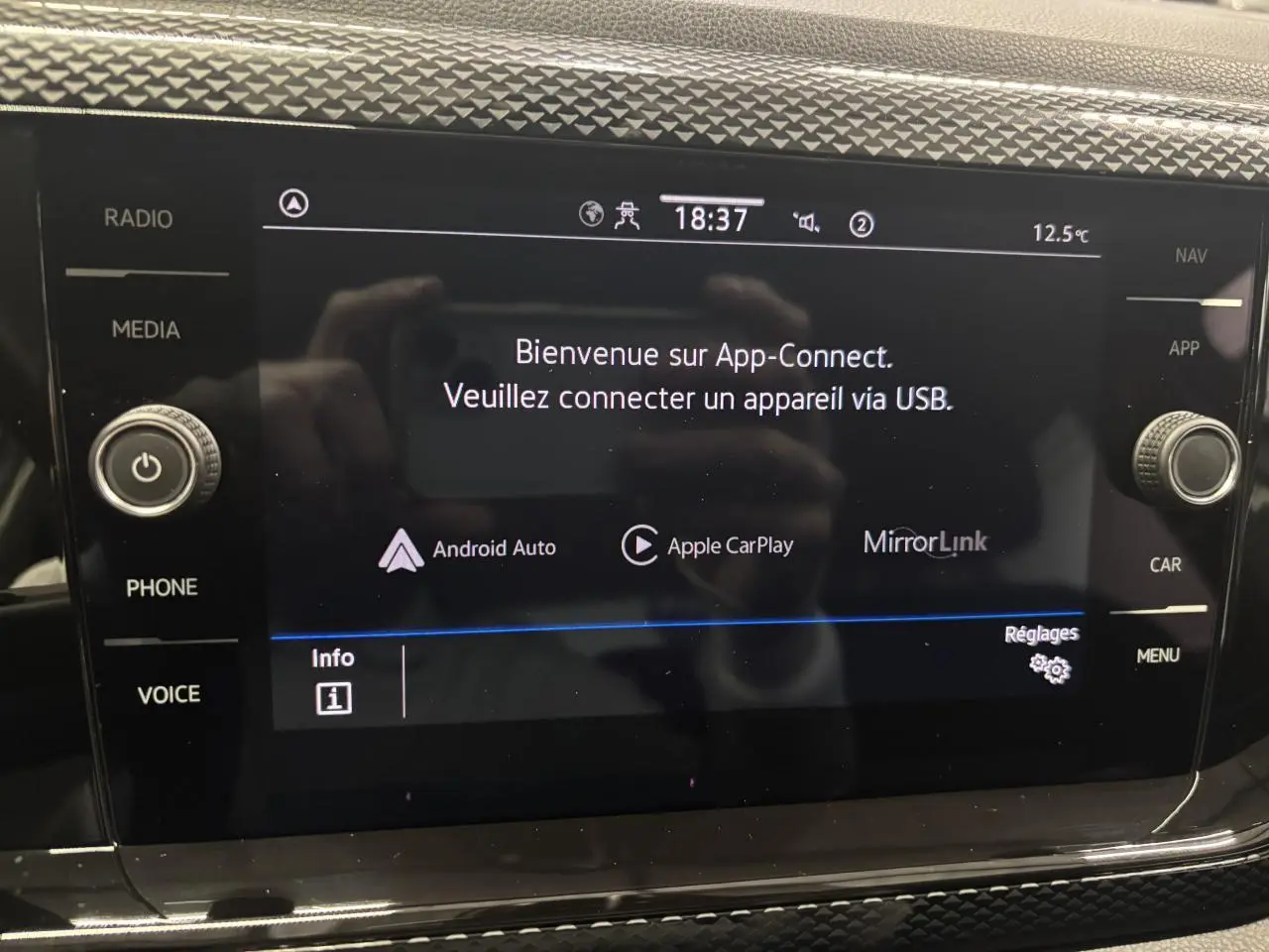 Écran tactile central du Volkswagen Taigo blanc 2023 affichant l'interface App-Connect avec commandes autour.