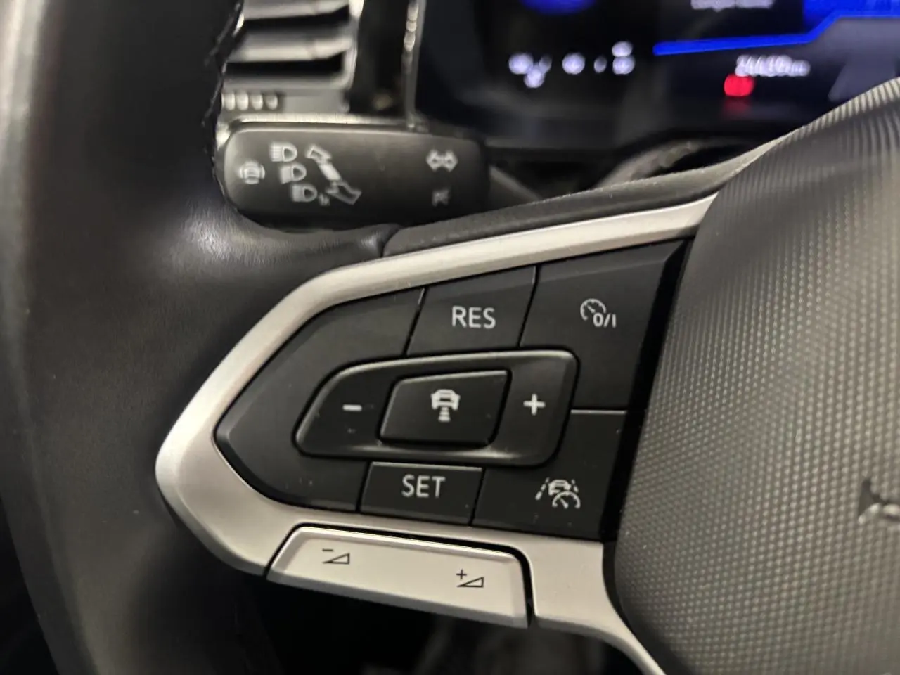 Gros plan sur les commandes de régulateur de vitesse au volant cuir noir du Volkswagen Taigo 2023.