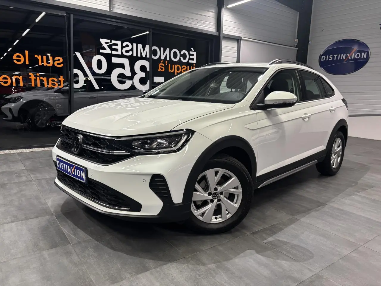 Volkswagen Taigo blanc en 3/4 avant droit, avec jantes alliage et calandre noire dans un showroom.