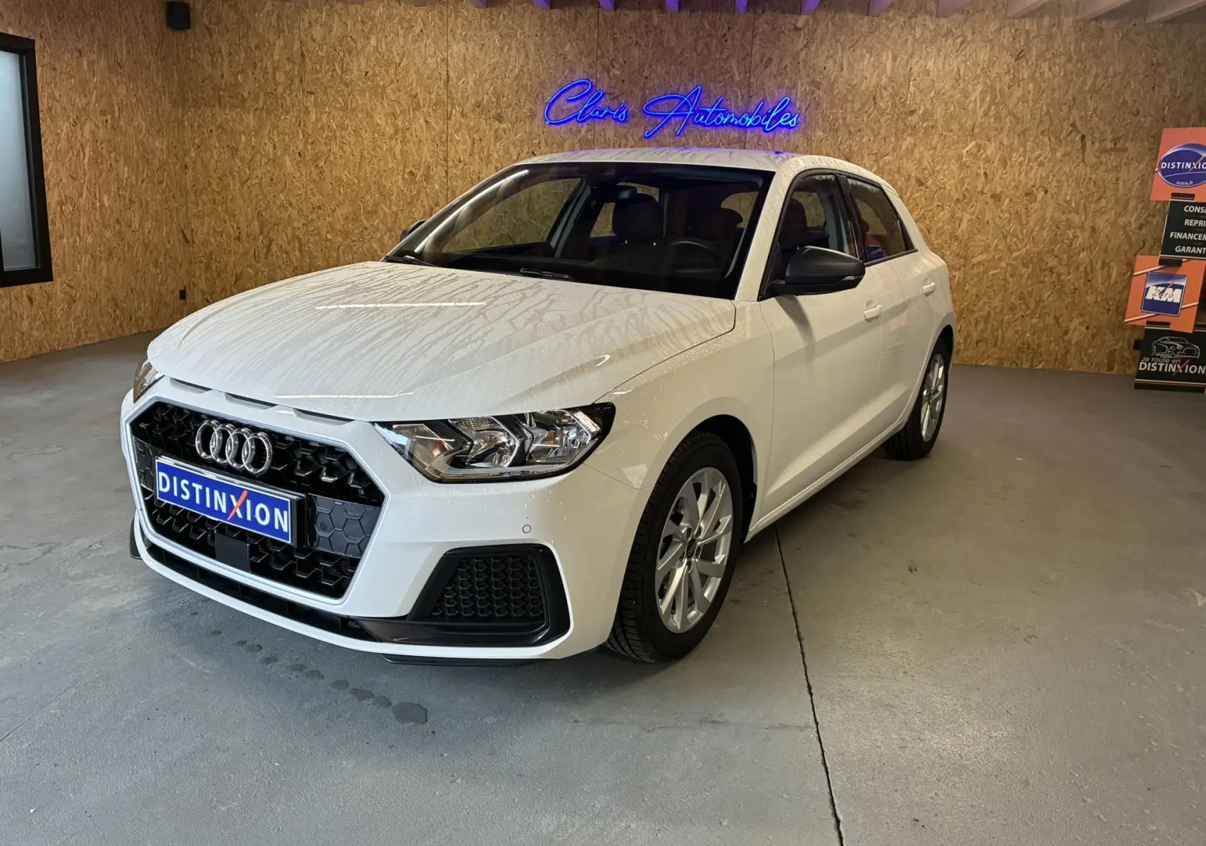 Audi A1 blanche vue en 3/4 avant droit, avec calandre noire et jantes alu 17 pouces dans un garage.