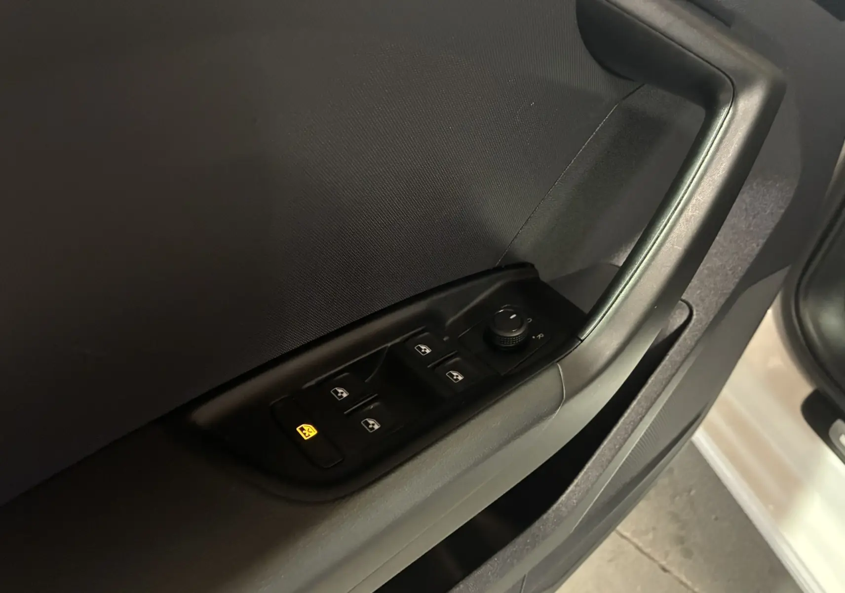 Gros plan sur la commande des vitres électriques et rétroviseurs sur la porte côté conducteur d'une Audi A1 blanche.