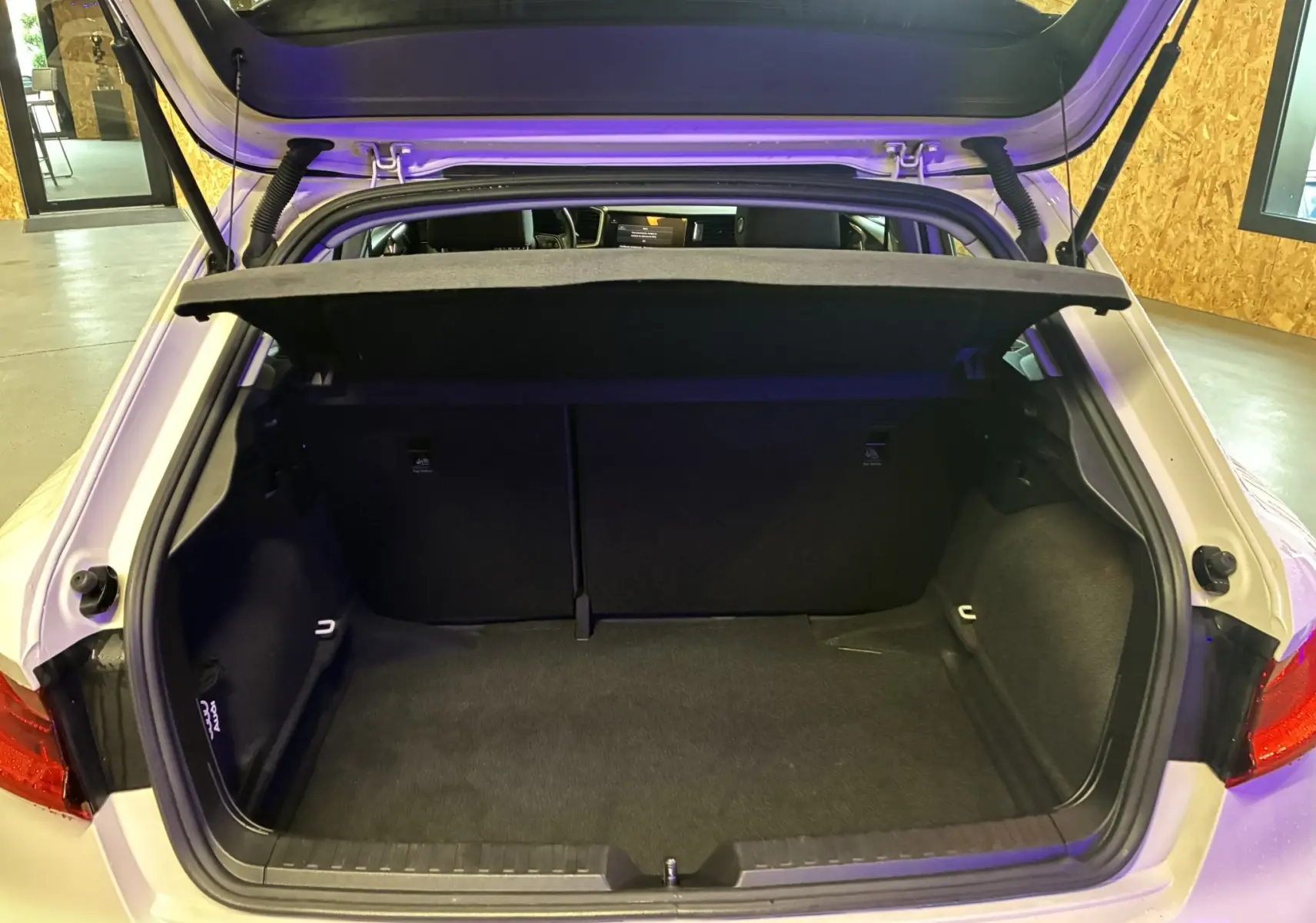 Coffre ouvert vu de l'arrière d'une Audi A1 blanche 2022, montrant l'espace de chargement vide et la plage arrière relevée.