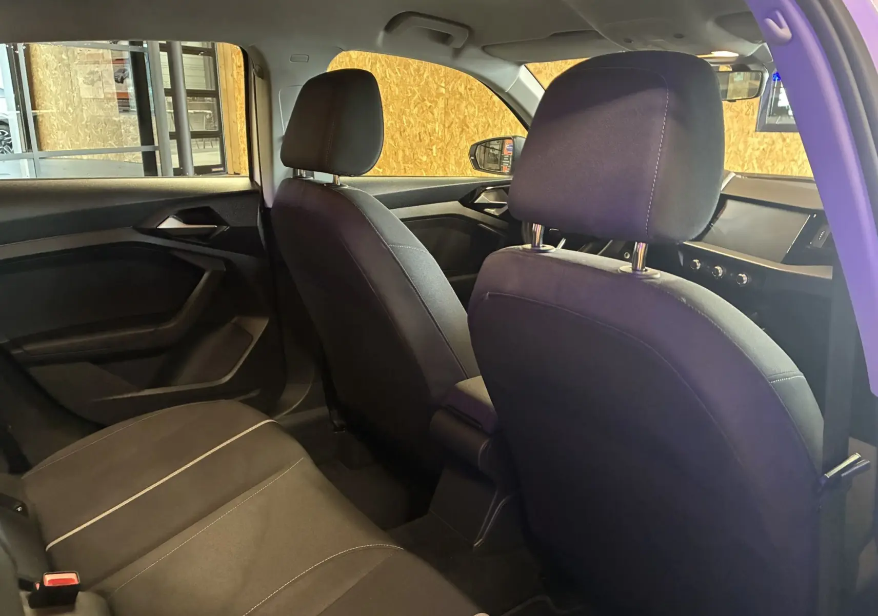 Vue intérieure arrière côté gauche de l'Audi A1 2022, sièges tissu noirs et tableau de bord visible au loin.