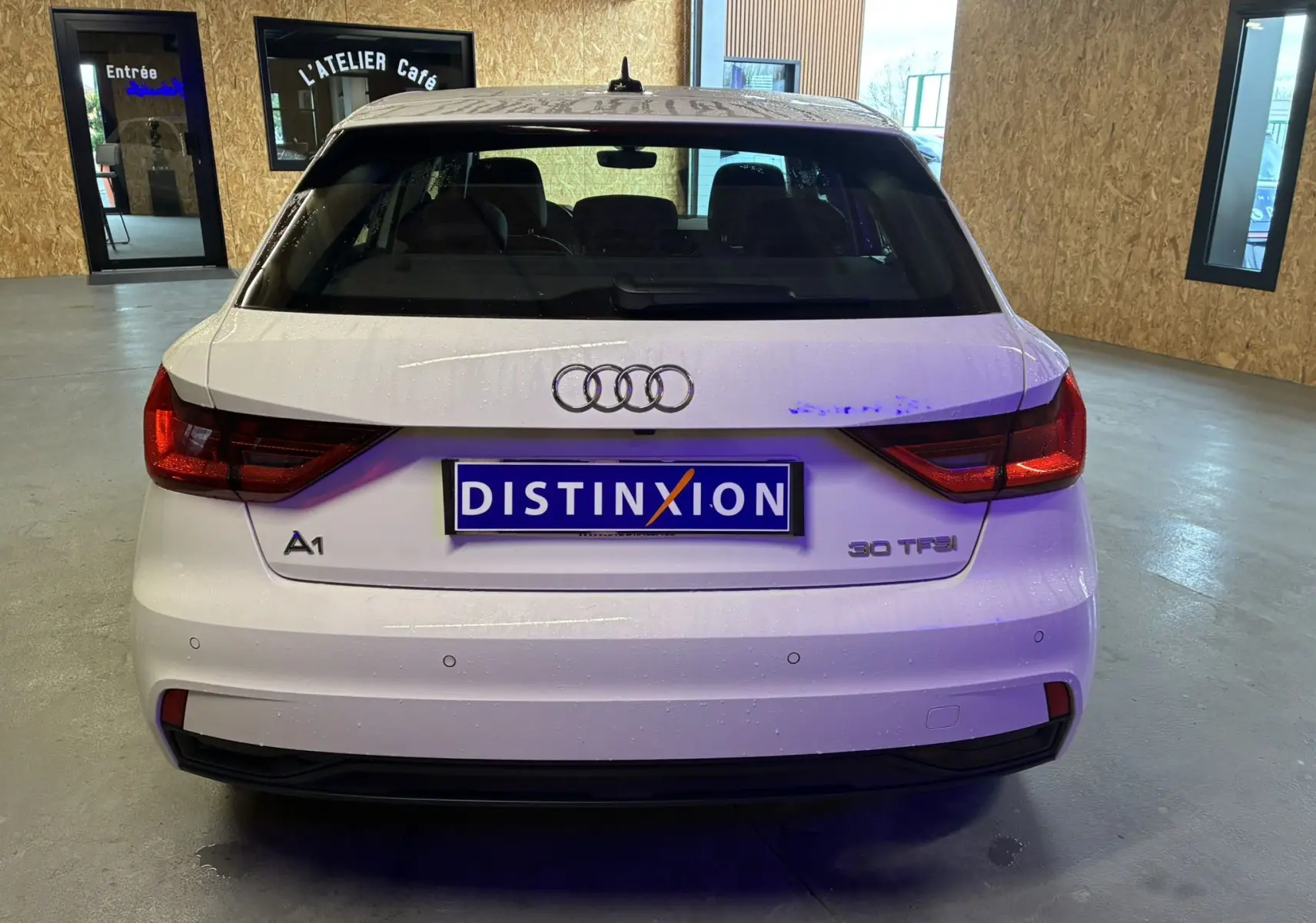 Vue arrière d'une Audi A1 blanche 30 TFSI avec feux LED et capteurs de stationnement visibles en intérieur.