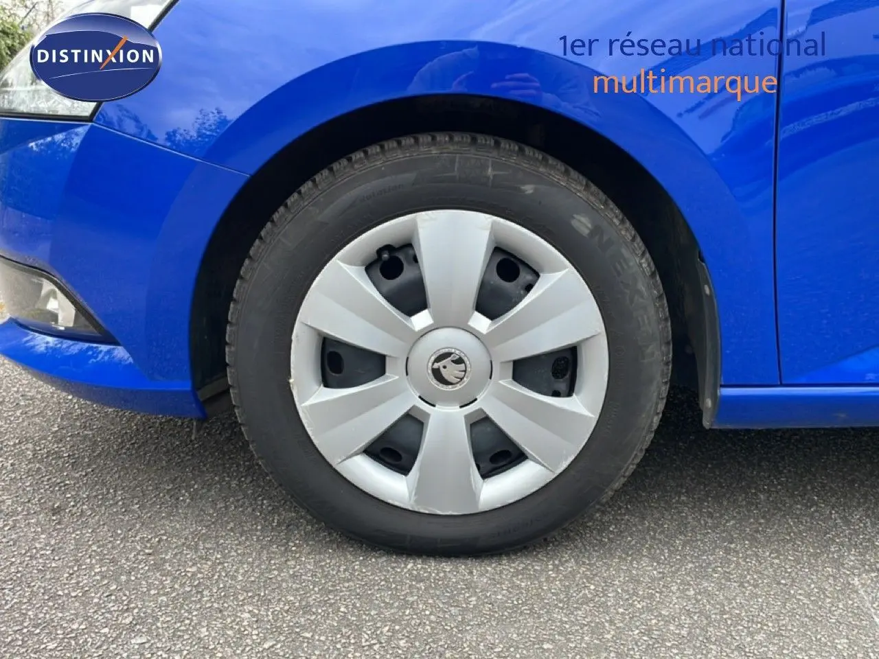 Gros plan sur la roue avant droite d'une Skoda Fabia bleu énergie, mettant en valeur la jante en plastique gris clair.