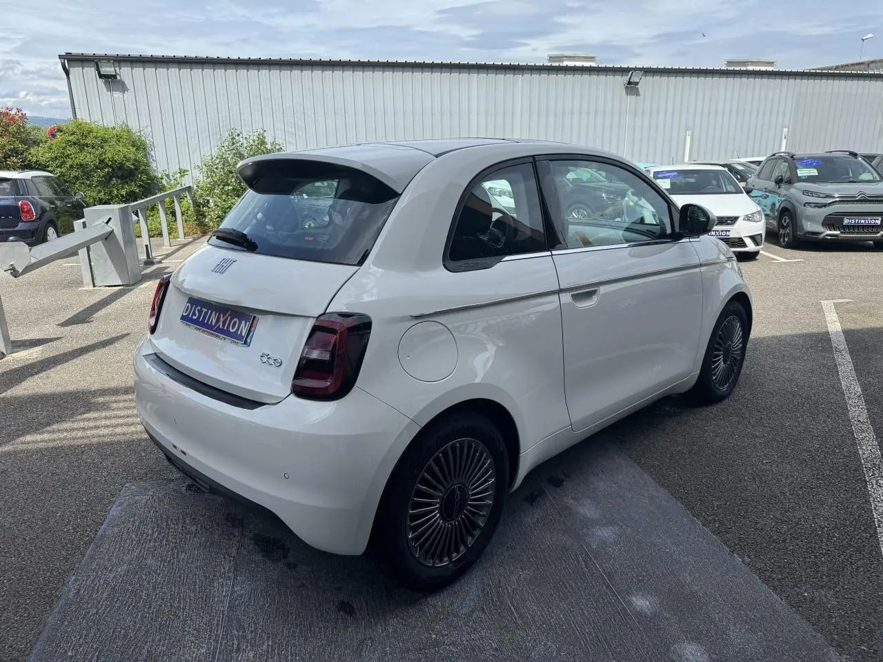 Vue 3/4 arrière droite d'une Fiat 500 électrique blanche avec jantes alliage 16'' et toit panoramique.