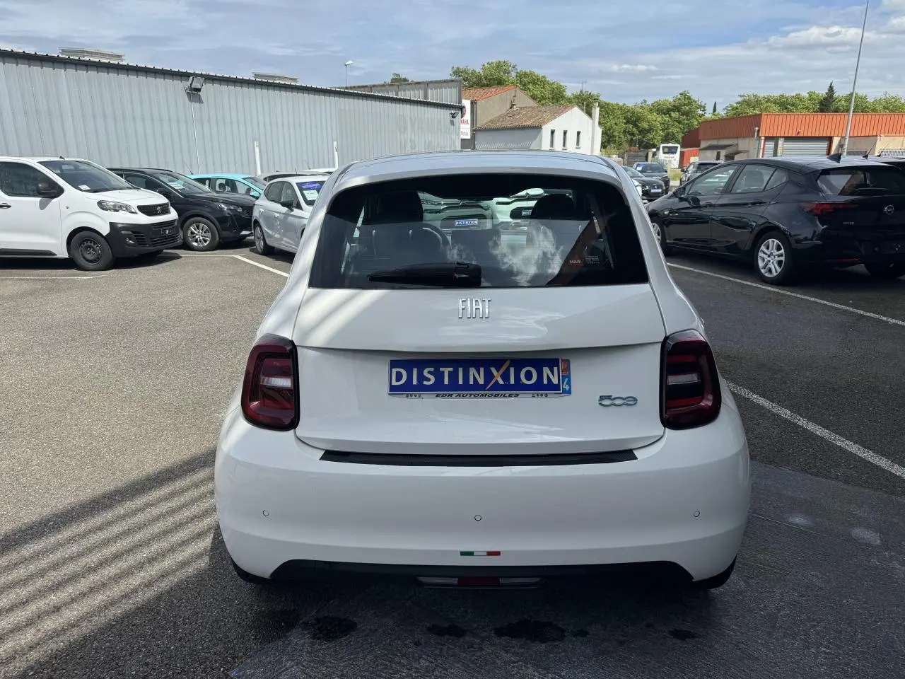 Vue arrière d'une Fiat 500 électrique blanche 2022 avec feux arrière foncés et logo FIAT visible.