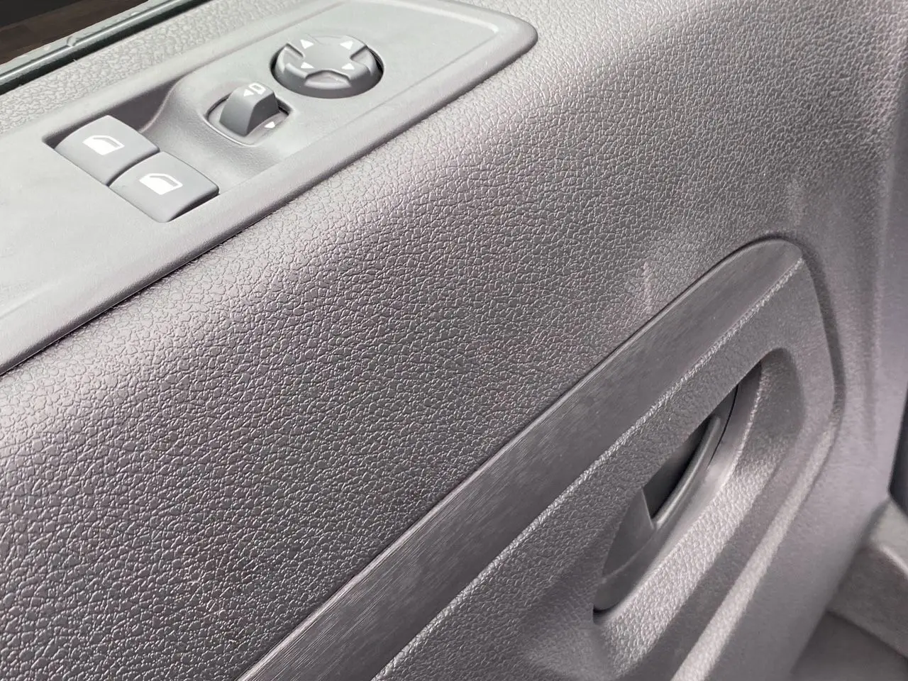 Gros plan sur la porte côté gauche de l’Opel Vivaro noir, montrant les commandes électriques des vitres et le bouton de réglage des rétroviseurs.