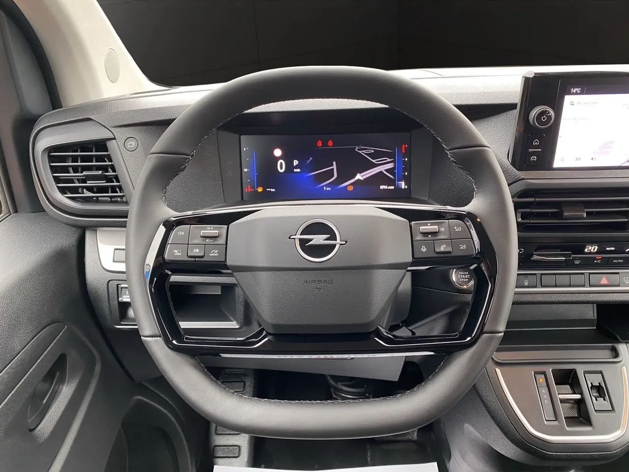 Vue rapprochée du volant noir et du tableau de bord numérique d'un Opel Vivaro 2025 avec commandes intégrées.