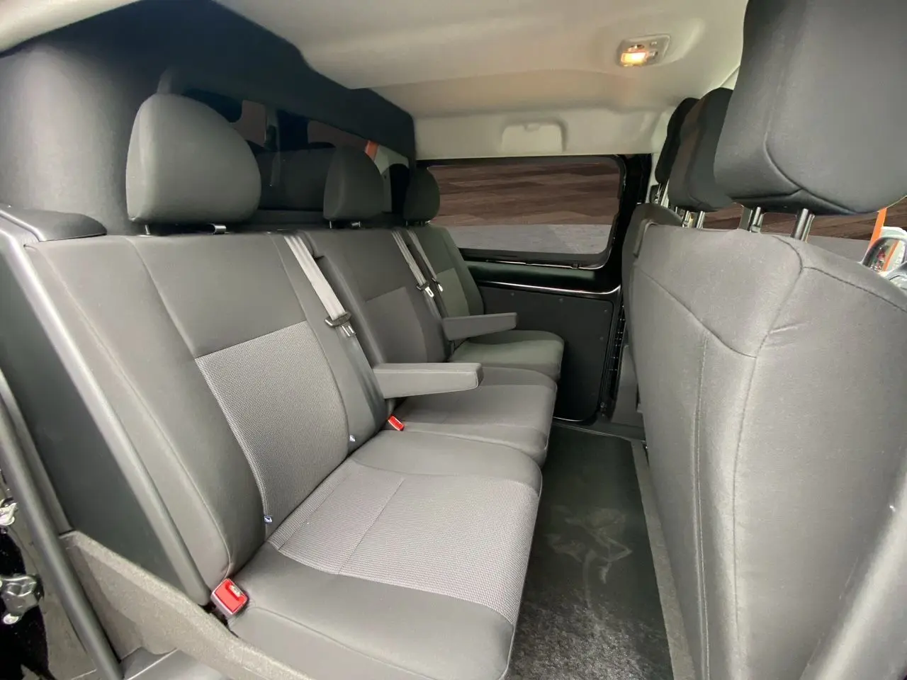 Vue intérieure côté droit des sièges arrière noirs en tissu du fourgon Opel Vivaro 2025 avec accoudoirs et ceintures de sécurité.