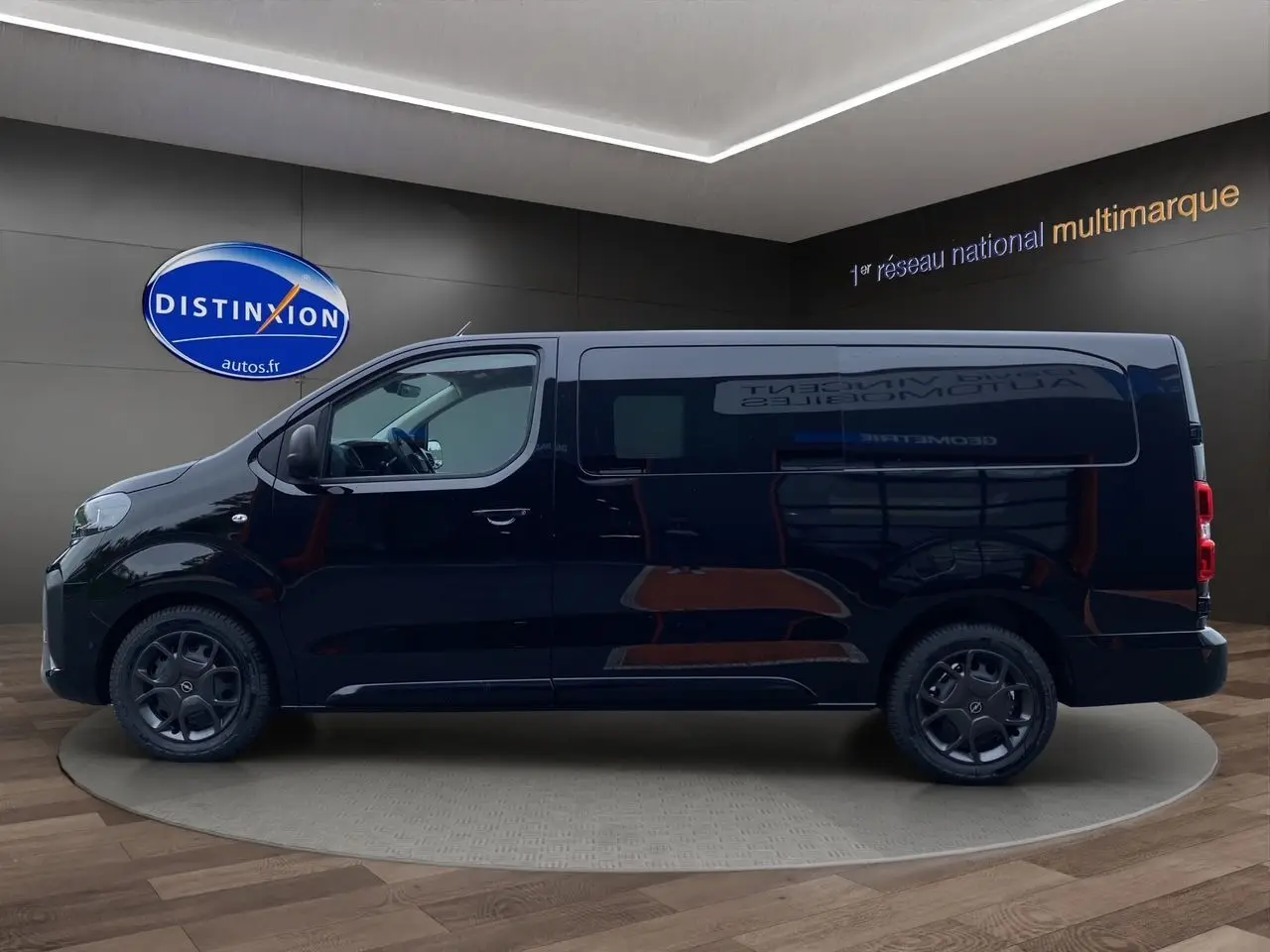 Profil côté gauche d'un Opel Vivaro noir 2025 avec jantes noires et vitres teintées en showroom.