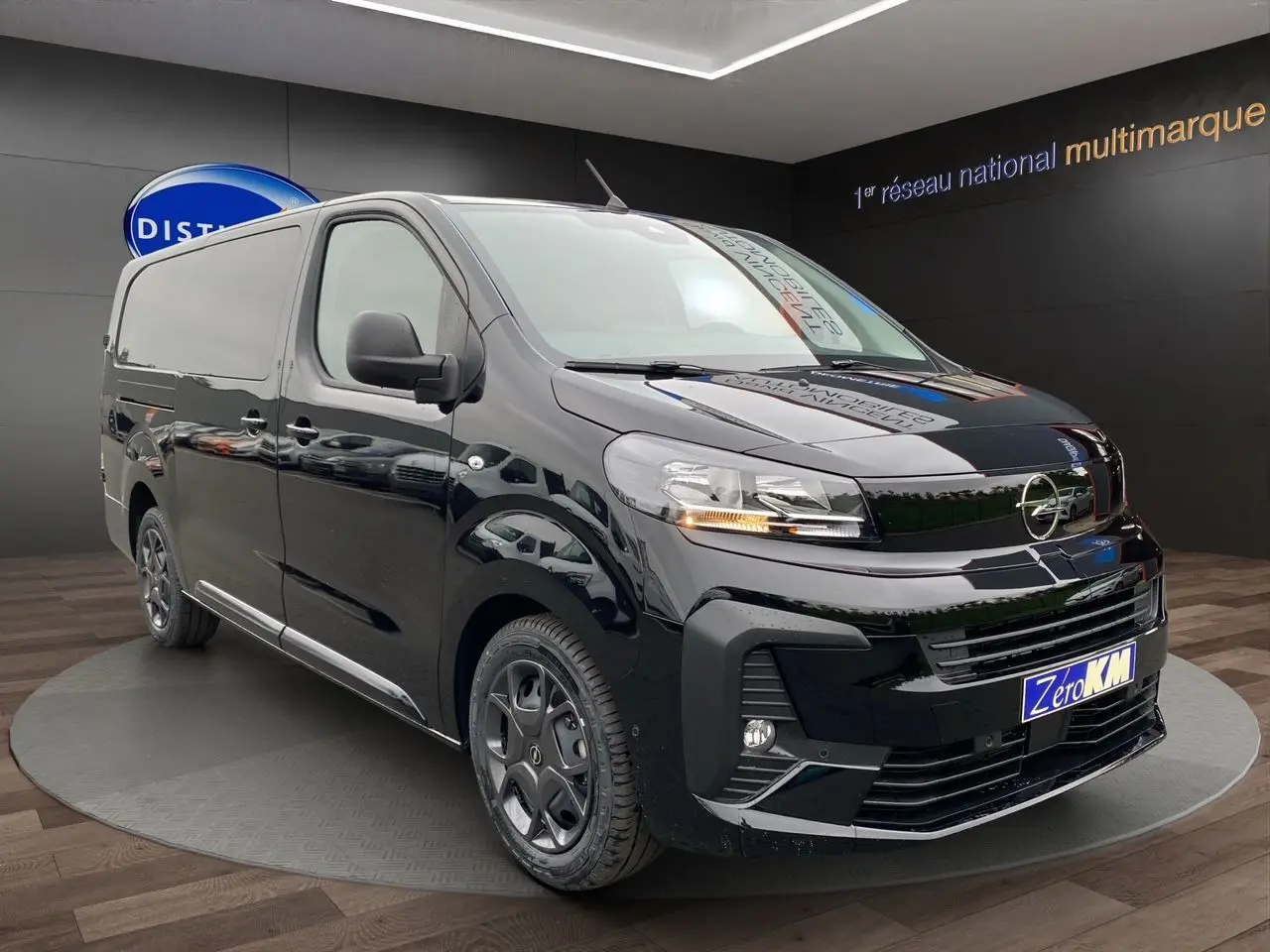 Vue 3/4 avant d'un Opel Vivaro noir 2025 avec attelage et jantes noires dans un showroom.