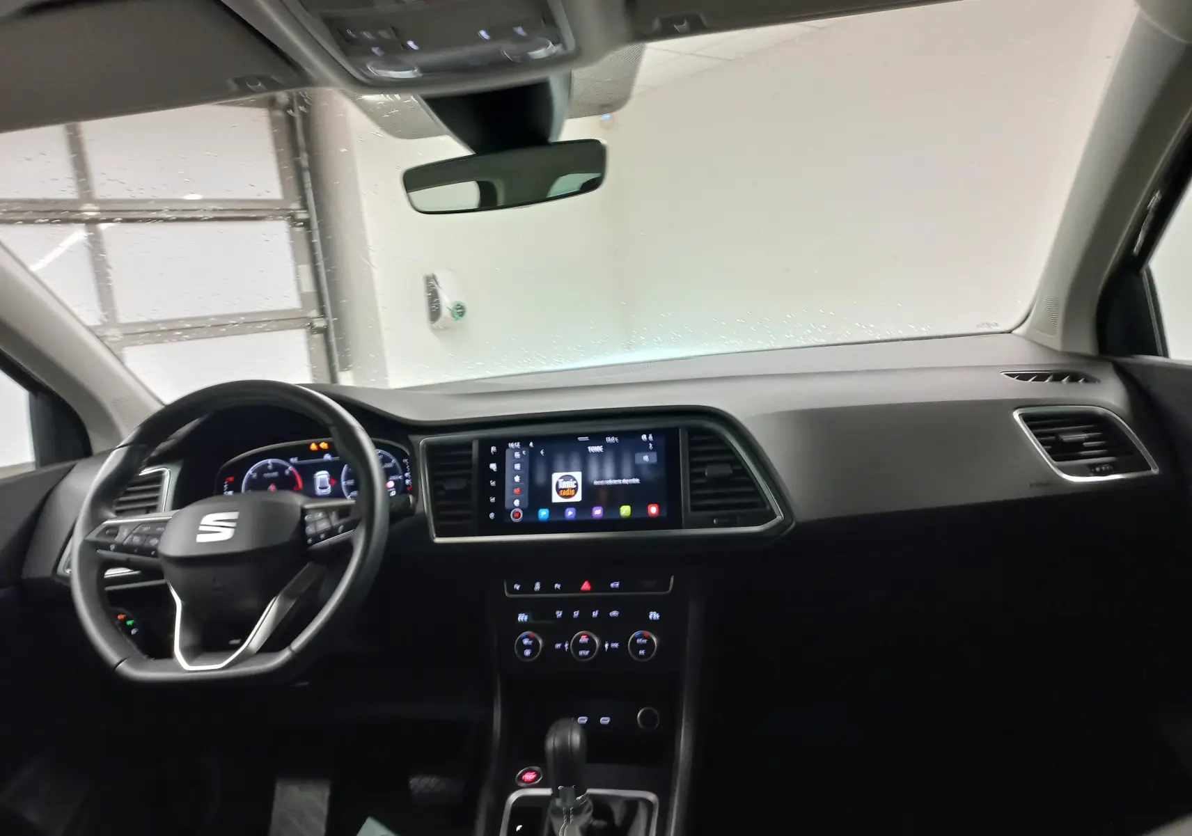 Intérieur du SEAT Ateca 2025 vu de face, tableau de bord noir avec écran tactile et volant multifonction.