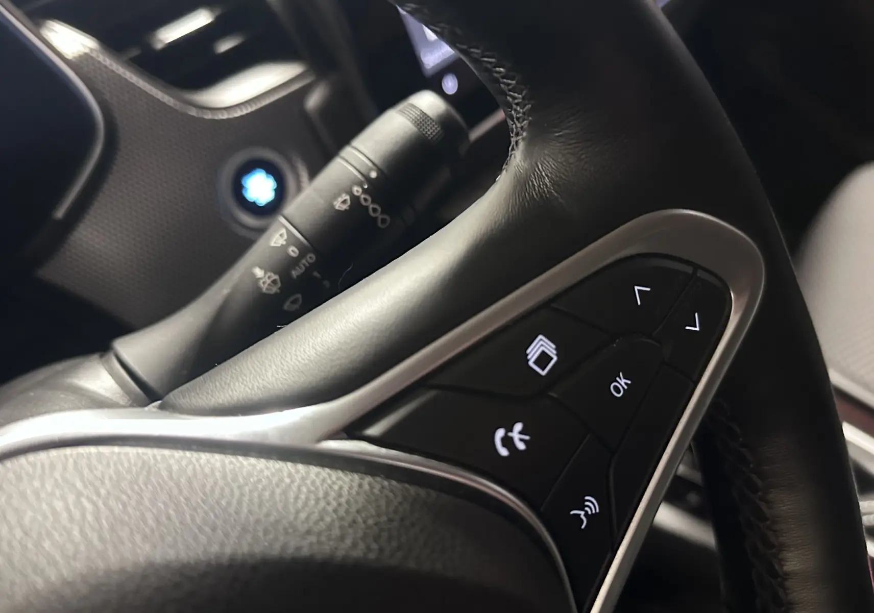 Gros plan sur les commandes au volant noir du Renault Arkana 1.6 E-Tech 145ch Intens, avec boutons multifonctions éclairés.