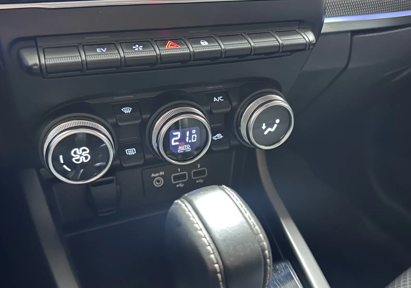 Gros plan sur la console centrale noire du Renault Arkana 1.6 E-Tech, avec commandes climatisation et levier de boîte auto.