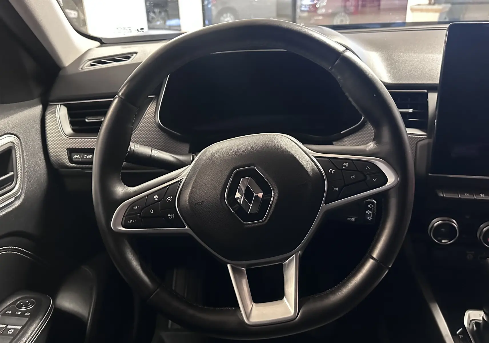 Vue intérieure centrée sur le volant noir de la Renault Arkana 1.6 E-Tech 145ch Intens avec tableau de bord et écran tactile.