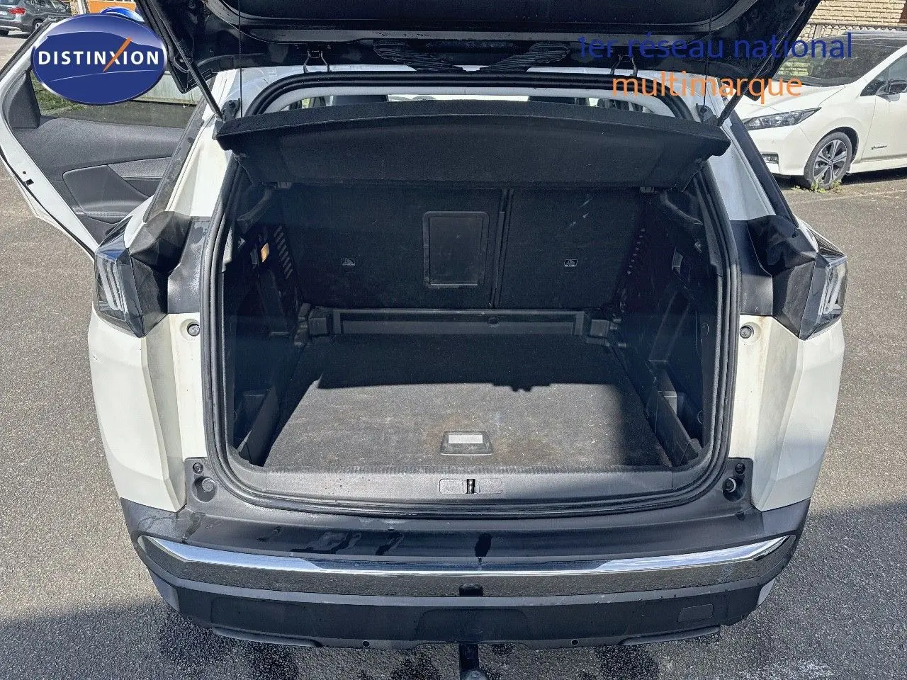Coffre ouvert vu de l'arrière d'un Peugeot 3008 blanc nacré métal, montrant l'espace de chargement vide.