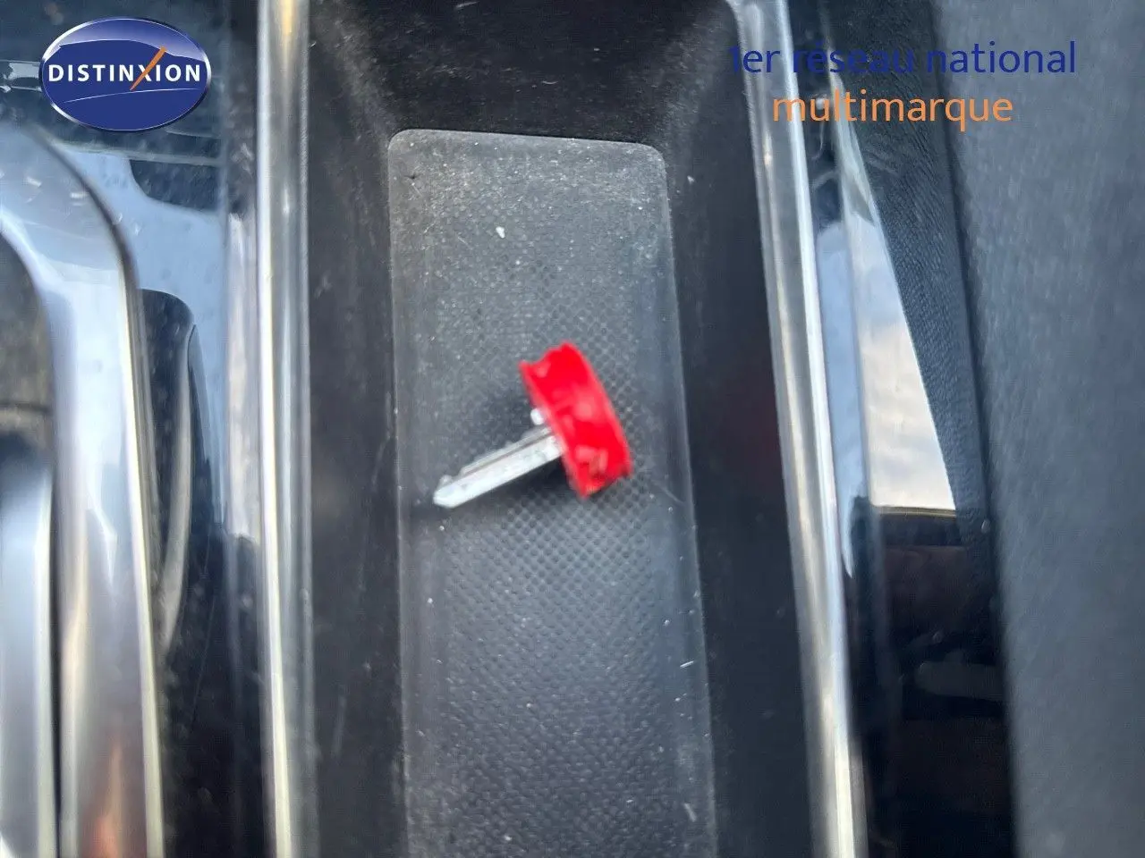 Gros plan sur la clé rouge posée dans le rangement central intérieur d'un Peugeot 3008 blanc nacré 2022.