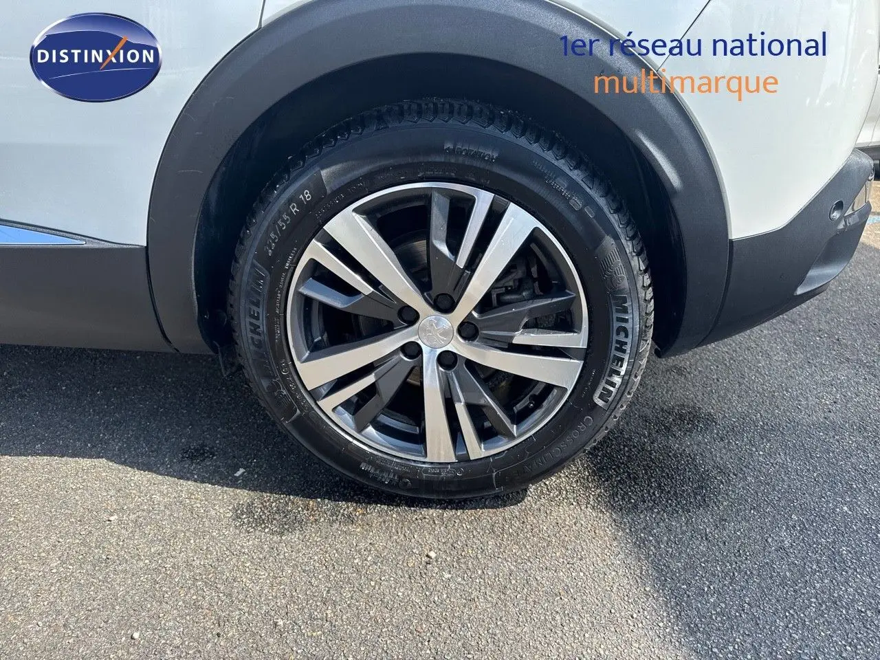 Gros plan sur la roue arrière droite d’un Peugeot 3008 blanc nacré avec jante alliage bicolore et pneu Michelin.